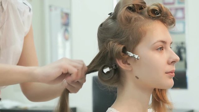 Master makes the curls to girl at the beauty salon