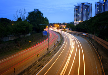 Fototapeta premium Light trails of cars at highways during blue hour.
