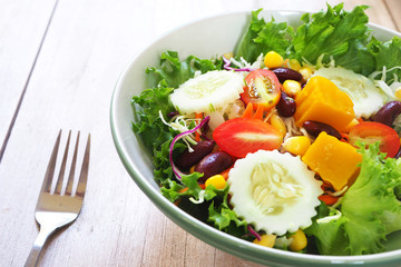 Close up of healthy mixed salad bowl on a wooden table.
