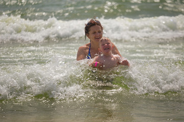 Mother giving son a swimming lesson in Sea with waves during summer