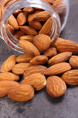 Almonds spilling out of glass jar on concrete structure