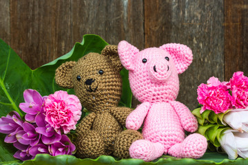 bear doll and pig doll with flowers on wood background