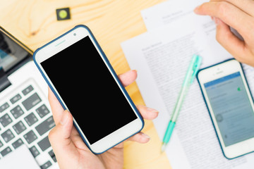 Business man hand is holding cell phone on wooden able with copy