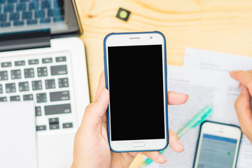 Business man hand is holding cell phone on wooden able with copy