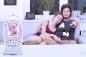 Couple watching TV not realising that their baby on the monitor is not sleeping