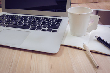 Office supplies with coffee cup and laptop in the office