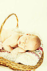 Sleeping cute newborn baby girl in the basket. One month old sweet child.