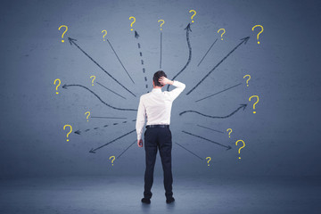 Businessman standing in front lines and question mark signs conc