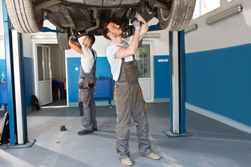 Mechanics working together under the car