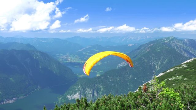 Austria, Obertraun, near 5 Fingers. Paraglider kicks and flying over the mountains, Hallstatter See and settlements. UHD