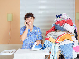 Caucasian young woman ironed clothes and talking on the phone.