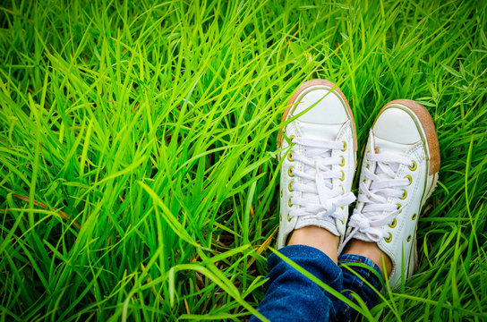 Shoes of a teenager woman who is sitting on grass field