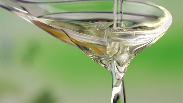 Pours oil on a salad spoon with green background