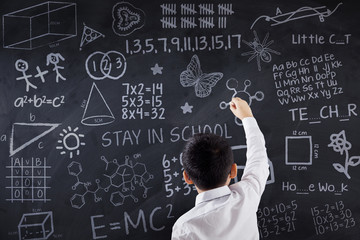 Schoolboy writing doodles on chalkboard