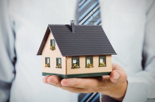 Realtor holding house miniature. Home finance concept