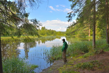 Fototapeta premium A fisherman catches a fish on the shore of a forest river