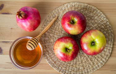 Honey, pomegranate and red apples on wood deck for Rosh Hashanah celebration. Jewish New Year Holiday.