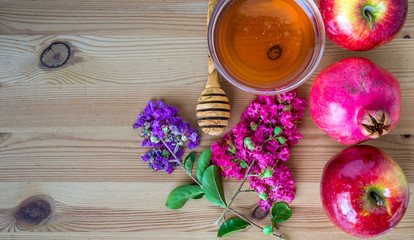 Honey, pomegranate and red apples on wood deck for Rosh Hashanah celebration. Jewish New Year Holiday.