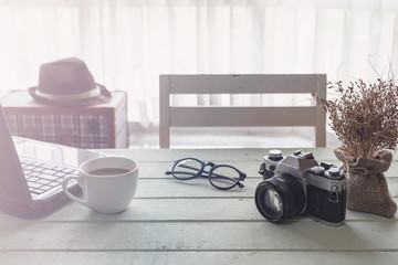 Cup of coffee and notebook on wooden table with sunlight