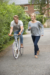 Young man on a bicycle with girl running alongside