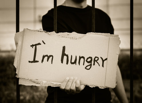 Teenager holds a sign on which is written in black marker, "I'm hungry."
