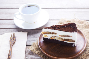 Close up of Tiramisu cake on a wooden plate with coffee.