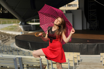 Uśmiechnięta dziewczyna z parasolką w amfiteatrze. - obrazy, fototapety, plakaty