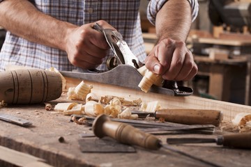 carpenter working with plane on wooden background