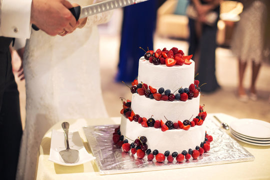 newlyweds cut wedding cake with berries