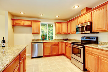 Bright kitchen room with light brown cabinets and steel appliances