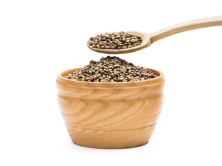 Hemp seeds in a wooden bowl with a spoon above it on white background