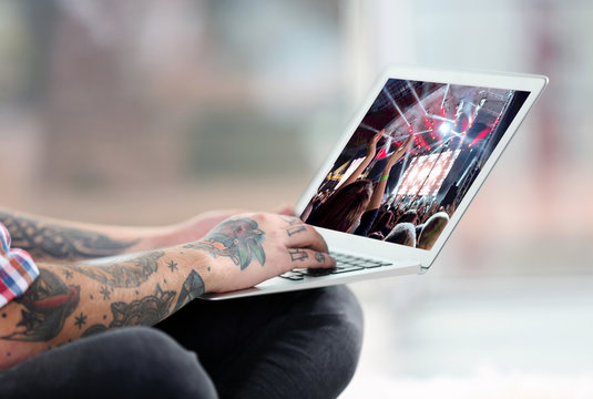 Young man with tattoo using laptop on a floor at home