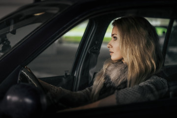 Fototapeta na wymiar City portrait of pretty blonde driver inside the car. Night scen