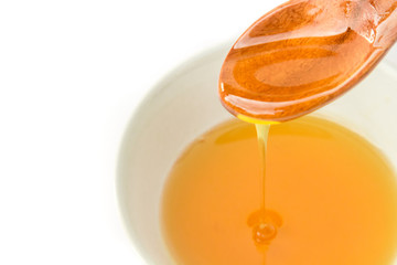 Closeup honey dripping from a wood spoon to bowl on white background, Healthy and beauty spa concept