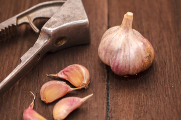 masher for garlic and garlic on a wooden background
