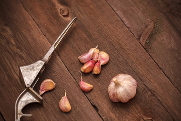 masher for garlic and garlic on a wooden background