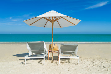 Beach chairs on the sand beach with cloudy blue sky