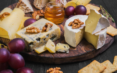 Assorted cheeses on round wooden board plate
