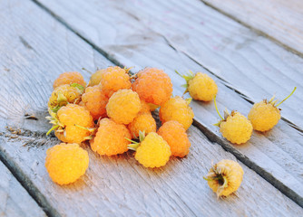 Yellow ripe raspberries on rustic wooden background, gardening and healthy food concept