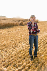 Modern female farmer with tablet on her wheat field