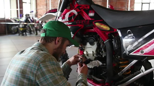 male sportsman repairing his enduro motorcycle