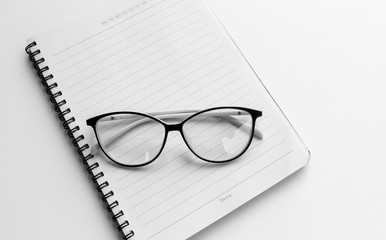 Glassesl on empty white notebook