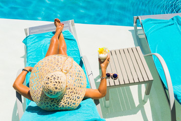 Woman at the poolside with pina colada cocktail - obrazy, fototapety, plakaty