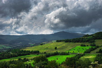 Fototapeta na wymiar Summer day landscape with cloudy sky, mountains, small houses. Carpathian Mountains. Ukraine. Europe.