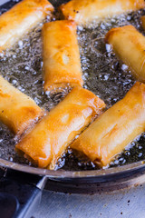 Spring rolls with prawns being fried.