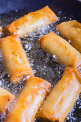 Spring rolls with prawns being fried.