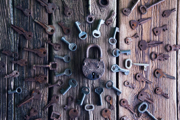 Old rusty padlock and keys on wooden background