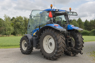 Modern blue tractor on a farmyard.