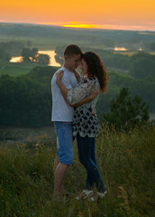 romantic couple embrace at sunset on outdoor, beautiful landscape and bright yellow sky, love tenderness concept, young adult people