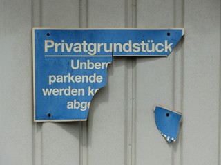 Kaputtes brüchiges blaues Schild Privatgrundstück an einem hellen Garagentor in Wettenberg...
